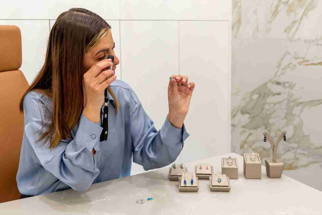 Jewellery appraiser examining rings with a loupe at Gold Exchange Universe in Sydney. Display of assorted jewellery including rings and earrings on the table for cash exchange.